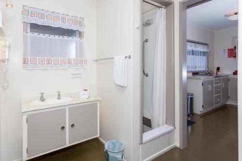 a white bathroom with a sink and a shower at Tairua Shores Motel in Tairua