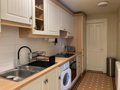 a kitchen with a sink and a washing machine at Self Catering Apartment- 11A Westbourne Place in Cobh