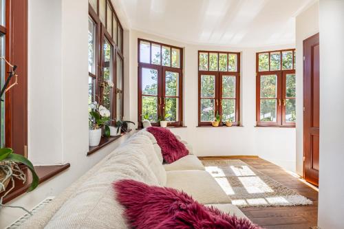 ein Wohnzimmer mit einem langen Sofa und Fenstern in der Unterkunft Kőszikla Vendégház a csendes pihenésre vágyóknak! in Kismaros