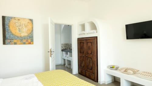 een witte slaapkamer met een bed en een tv aan de muur bij Domaine de la Bedosse in Alès