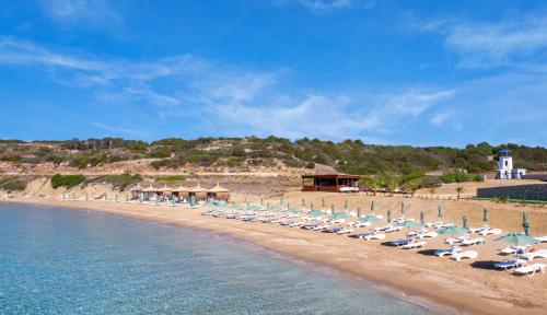 a beach with chairs and umbrellas and the ocean at Blue Sea Karpasia Hotel in Rizokarpaso