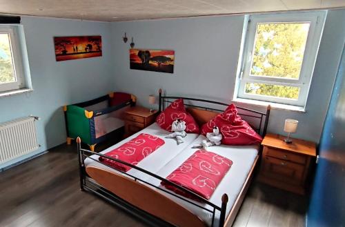 een slaapkamer met een bed met rode kussens bij Ferienwohnung Hobbyhof Deggenhausertal in Deggenhausertal