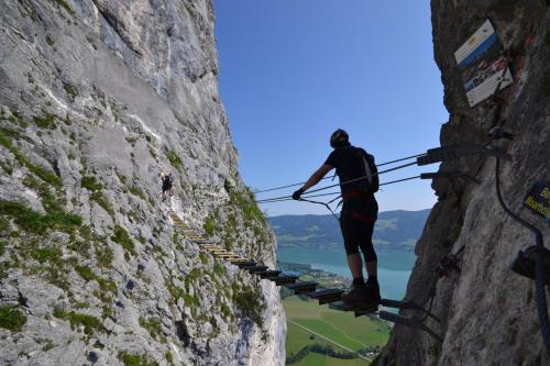 a man is standing on a climbing rope on a mountain at Gesundheitshof Lohninger in Mondsee