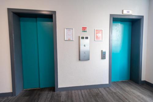 two elevators in a room with blue and green doors at easyHotel Croydon in Croydon