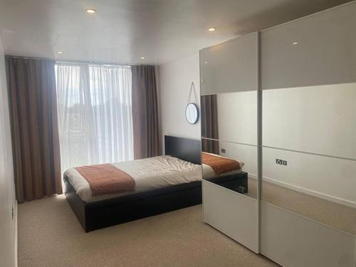 Schlafzimmer mit einem Bett und einer Glaswand in der Unterkunft Luxurious 2 bedroom flat with en-suite bedroom in South Norwood