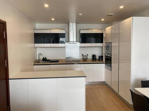 una cucina con armadi bianchi e piano di lavoro di Luxurious 2 bedroom flat with en-suite bedroom a South Norwood