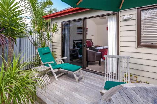 a patio with two chairs and an umbrella at Tairua Shores Motel in Tairua