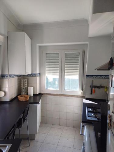 a kitchen with white cabinets and a black counter top at Amoreira Room I and II in Lisbon