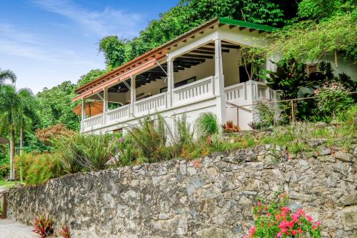 a house with a stone wall in front of it at Casa Grande Mountain Retreat - Adults Only in Utuado