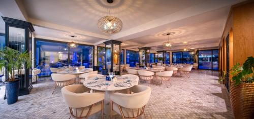 a restaurant with white tables and chairs and windows at Blue Sea Karpasia Hotel in Rizokarpaso