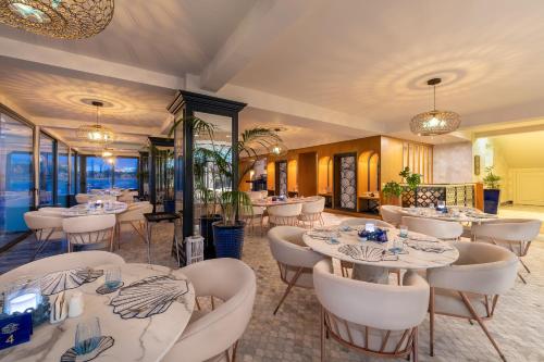 a restaurant with white tables and white chairs at Blue Sea Karpasia Hotel in Rizokarpaso