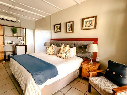 een slaapkamer met een groot bed en een stoel bij Biweda Nguni Lodge in Mkuze