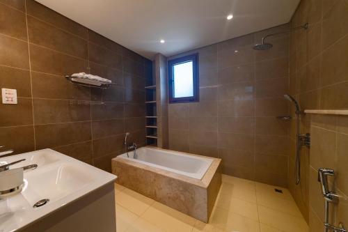 een badkamer met een bad en een wastafel bij Palm House in Salalah