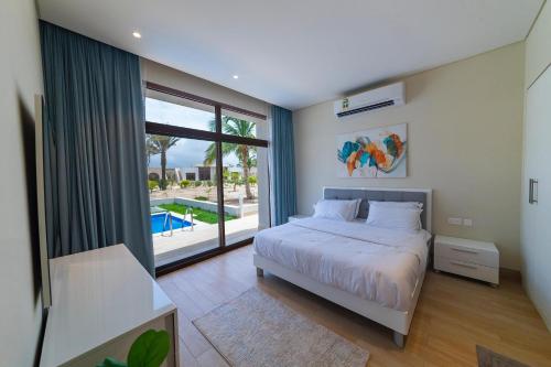 um quarto com uma cama e uma grande janela em Palm House em Salalah