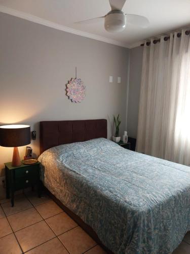 a bedroom with a bed with a blue comforter at Quarto Aconchegante! in Sorocaba