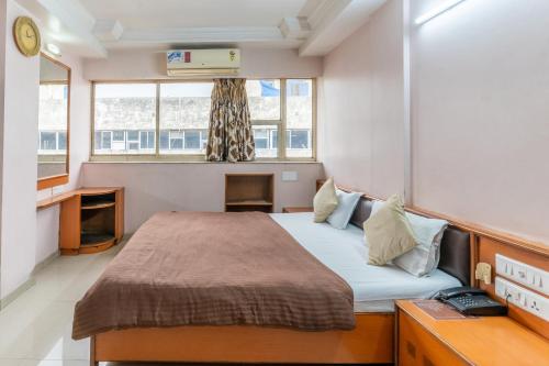 a small bedroom with a bed and a window at Hotel Sanmati in Ahmedabad