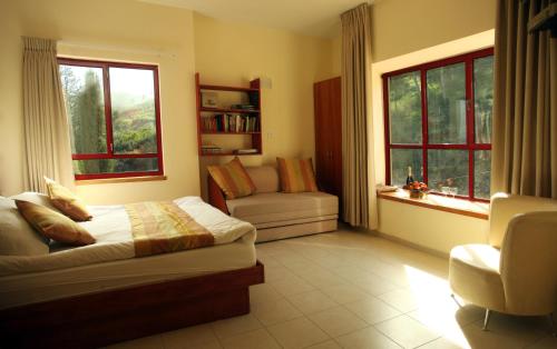 a bedroom with a bed and a couch and windows at Gilboa Guest House - Benharim in Gid‘ona