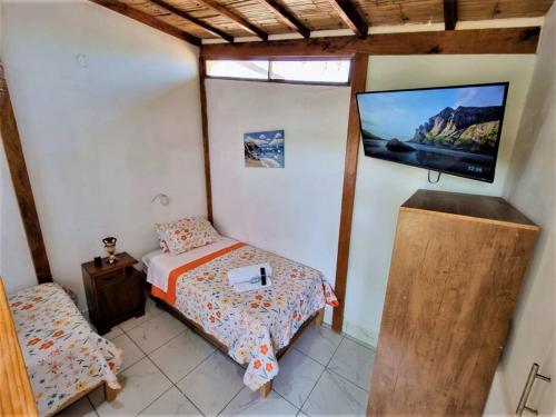 1 dormitorio con 1 cama y TV de pantalla plana en Bright Bungalow 3 -Close to Ocean, en Zorritos
