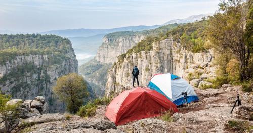 a man standing on top of a mountain next to a tent at A dream house with a dream view in ROYAL PARK in Alanya