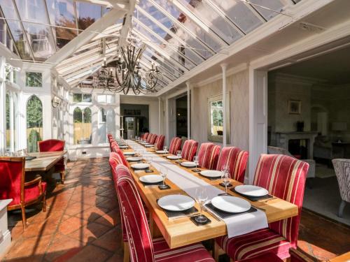 a large dining room with a long table and red chairs at Valley View in Dalton in Furness