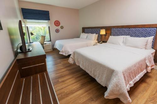 1 dormitorio con 2 camas y TV. en Hampton By Hilton San Jose Airport Costa Rica, en Alajuela