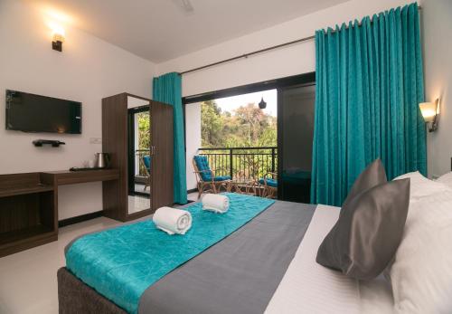 a bedroom with a bed with a television and a balcony at Aloha Holiday Resort in Baga