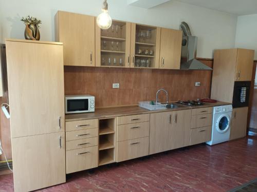 La cuisine est équipée de placards en bois, d'un évier et d'un four micro-ondes. dans l'établissement Apartament 2 dormitoare, à Ploieşti