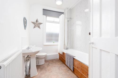 a bathroom with a sink and a toilet and a bath tub at Spacious 3 Bed House With Free Parking in Doncaster