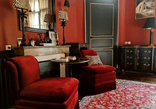 a living room with red walls and a chair and a table at Le 1825, une suite luxueuse au coeur de la ville in Nantes