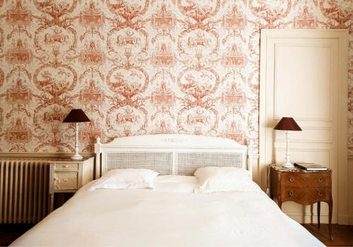 una camera da letto con un letto bianco e carta da parati di Le 1825, une suite luxueuse au coeur de la ville a Nantes