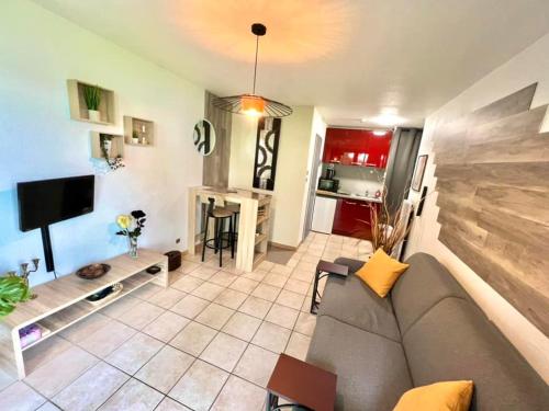 a living room with a gray couch and a kitchen at Joli studio cosy, vue magnifique et terrasse privée in Gérardmer