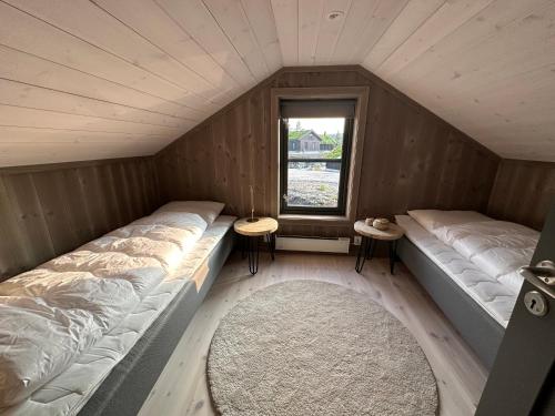 DrangedalにあるHelårs moderne familiehytte med wifi, billader, ski inn, ski ut og utmerket beliggenhetのベッド2台と窓が備わる小さな客室です。