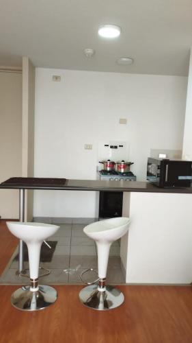 uma cozinha com dois bancos brancos e um balcão em Apartamento Fátima em Lima