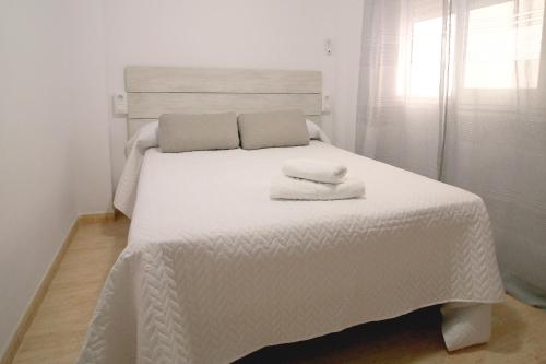 Una cama blanca con dos toallas encima. en Luna de Garrucha, en Garrucha