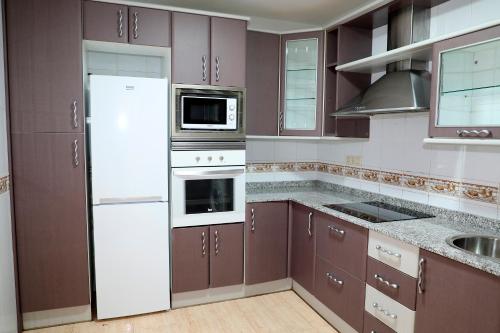 una cocina con electrodomésticos blancos y armarios marrones en Luna de Garrucha, en Garrucha
