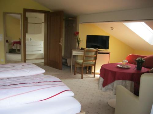 a bedroom with a bed and a desk with a television at Pension Schlömmer in Sankt Gilgen
