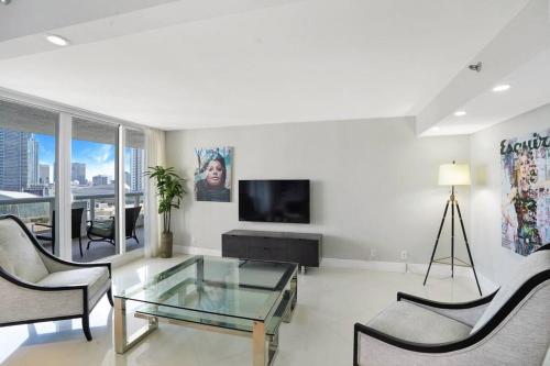 a living room with a glass table and a tv at Meet Me in Miami! Impressive Miami Skyline Views in Miami