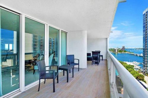 a balcony with chairs and tables and a view of the water at Meet Me in Miami! Impressive Miami Skyline Views in Miami