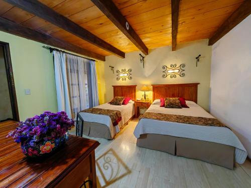 a hotel room with two beds and a vase of flowers at Hotel Casavieja in San Crist&oacute;bal de Las Casas