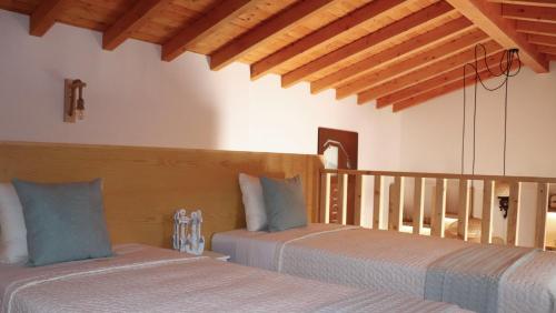 two beds in a room with wooden ceilings at Casa Ponte de Espindo in Lousada