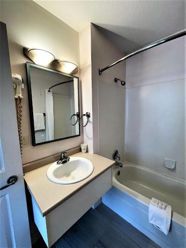 a bathroom with a sink and a mirror and a tub at Super 8 by Wyndham Lake Country/Winfield Area in Winfield