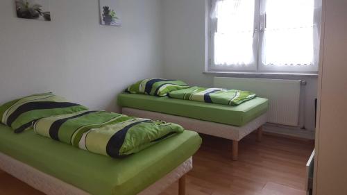 two green beds in a room with a window at holiday apartment essen 3 in Essen
