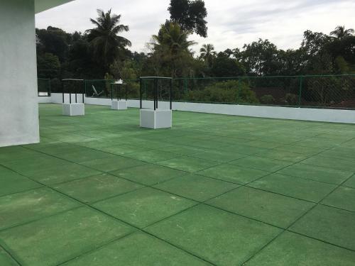 a green tennis court with two white tables on it at Everdew Kandy Rooms in Kandy
