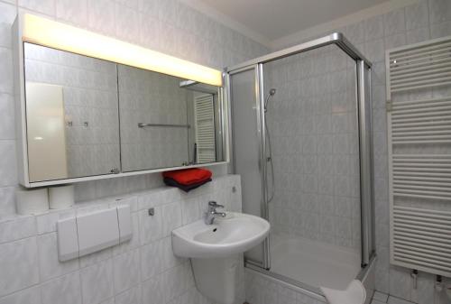 La salle de bains blanche est pourvue d'un lavabo et d'une douche. dans l'établissement Ferienwohnung L408 für 2-4 Personen an der Ostsee, à Brasilien