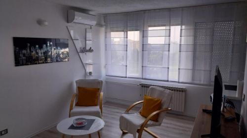 Apartman Enio في فوكوفار: غرفة معيشة مع كرسيين وطاولة
