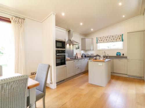 a kitchen with white cabinets and a table and chairs at Clipsham in Cottesmore