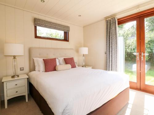 um quarto com uma grande cama branca e uma janela em Clipsham em Cottesmore