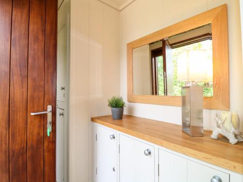 a bathroom with a mirror and white cabinets and a window at Clipsham in Cottesmore