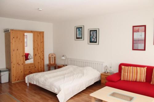 a bedroom with a bed and a red couch at Ferienappartement K315 für 2-4 Personen in Strandnähe in Schönberg in Holstein