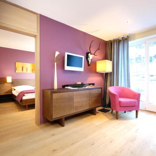 a bedroom with a purple wall with a desk and a pink chair at Apparthotel Sonne in Obertauern